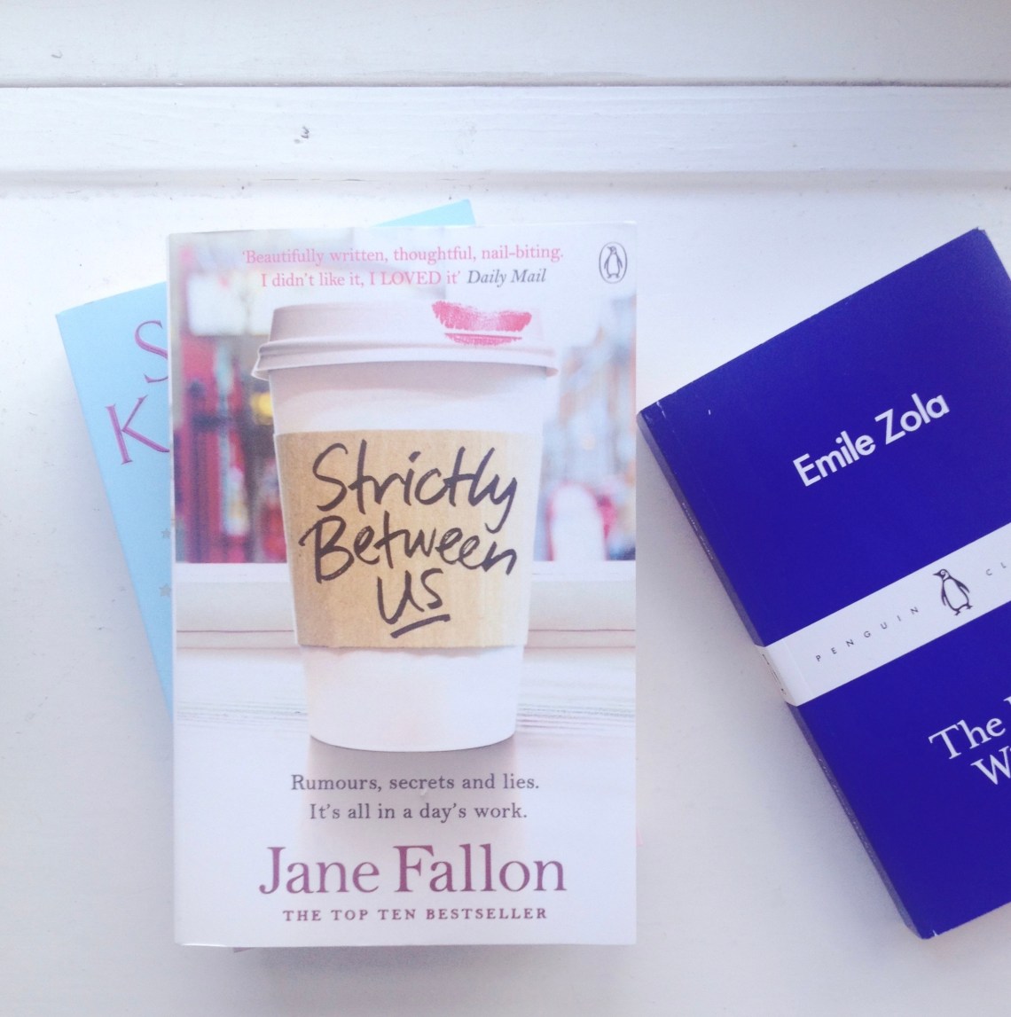 Tre bøger ligger i en vindueskarm Emile Zola, der er en blå bog og Strictly Between Us, der har et billede af en kaffekop på forsiden